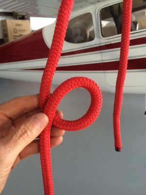 With lower end of tie down rope securely anchored to the ground, run the loose end thru the airplane tie down ring. Form a loop in the rope between the tiedown ring and the ground anchor.