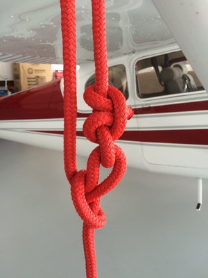 While holding tension by pinching where the loose end goes thru the second loop, tie off the loose end at the second loop with a couple of half-hitches. To re-tension, untie the loose end and re-tension then tie it off again without loosing tension on the tie down.